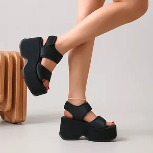 Vue latérale montrant des sandales compensées noires à larges brides velcro sur mannequin