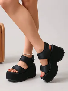 Gros plan de sandales compensées noires à plateforme avec brides velcro réglables sur un mannequin
