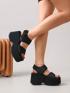 Gros plan sur des sandales compensées noires à semelle épaisse et Velcro.