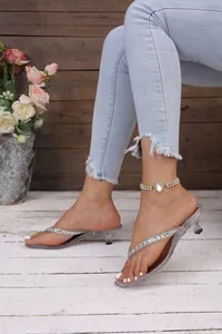 Dettaglio di eleganti sandali trasparenti infradito con cinturini in strass lucidi