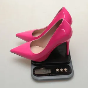 Detailed shot of shiny pink pointed-toe stiletto pumps being weighed on a scale