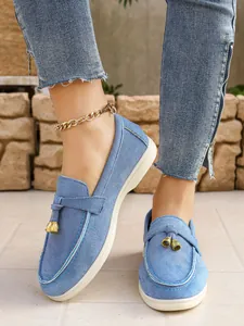 Close-up of blue denim loafers featuring elegant gold bell-shaped tassel accents.