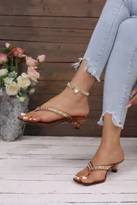 Primo piano di eleganti sandali infradito marroni da donna con decorazioni in strass