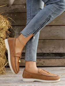 Detail view of brown suede loafers for women with gold-tone hardware and white soles