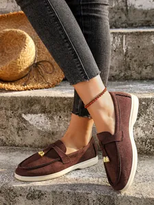 Casual brown suede women's slip-on loafers with a stylish golden buckle on model