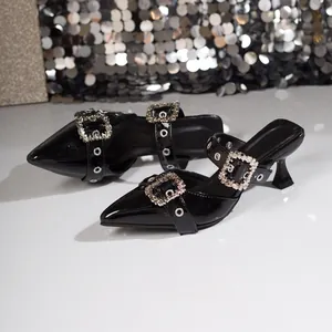 Detail von schwarzen Lackleder-Pumps mit funkelnden Kristallschnallen.