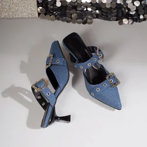 Detailansicht der blauen Denim-Mules mit spitzer Zehenpartie und funkelnden Kristallschnallen.