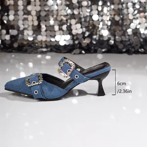 Seitenansicht der Pantolette aus blauem Denim mit Strass-Schnallen und 6 cm Absatz.