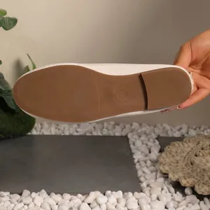 Close-up detail of the durable brown non-slip rubber sole on women's beige flat shoes