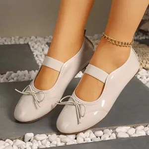 Macro view of elegant beige patent leather Mary Jane flats with a decorative bow