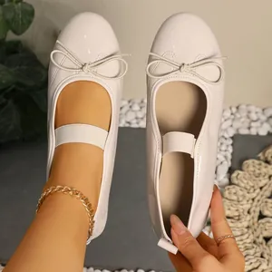 Detail of cream patent leather Mary Jane ballet flats with cute bow and elastic strap