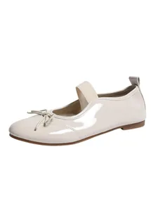Detailed side view of elegant cream white patent leather Mary Jane flat shoes with a bow