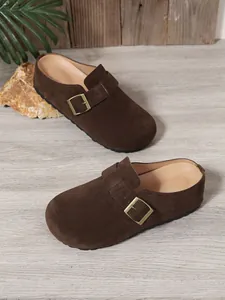 Detailed view of brown suede slip-on mules with gold buckle strap and flat sole