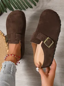 Close-up of casual brown suede mule clogs with a stylish adjustable buckle strap