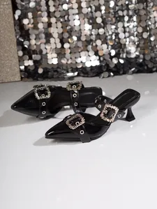Detailansicht von schwarzen Lackleder-Mules mit spitzen Zehen und Glitzerschnallen