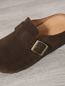 Close-up of dark brown suede mule shoe featuring a vintage brass buckle metal detail