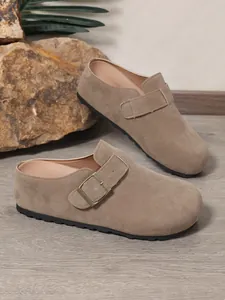 Detailed side view of women's taupe suede slip-on mules with an adjustable metal buckle.