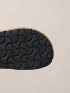 Detail of the black anti-slip sole with wavy tread for women's slide sandals.