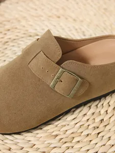 Detailed macro shot of brown suede slip-on mule with antique bronze buckle detail