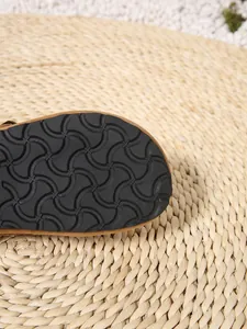 Close-up view of the black anti-slip textured pattern on the sole of a slide sandal.