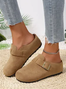 Close-up view of women's casual beige suede mules featuring a buckle strap on a straw mat