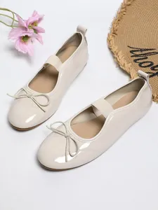 Close-up detail of elegant cream patent leather ballet flats with bow and strap