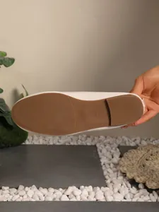 Detail shot of a women's cream ballet flat shoe showing the anti-slip brown sole