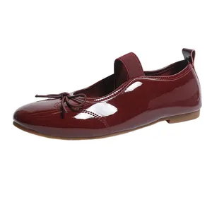 Side view of a burgundy patent leather flat shoe with an elegant bow and elastic strap