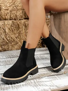 Close-up view of women's black suede Chelsea boots featuring chunky platform soles