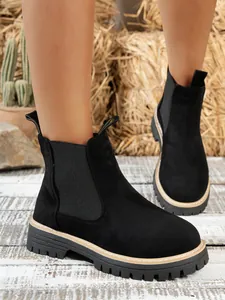 Close-up detail of black suede Chelsea boots featuring rugged sole and beige stitching