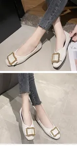 Elegant white ballet flats featuring a decorative crystal square buckle worn by a model