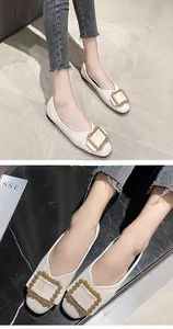 Detailed view of elegant white ballet flats featuring a decorative gold square buckle.
