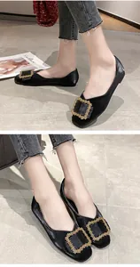 Detail view of black pointed-toe ballet flats with iconic gold beaded buckle decoration.