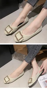 Close-up detail of beige pointed toe flats with elegant rhinestone square buckle.