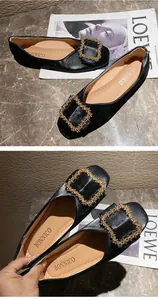 Detailed view of elegant black flat loafers with signature gold beaded square buckle