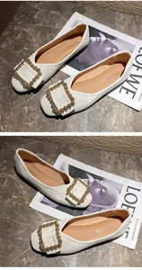 Detailed top view of white ballet flats with ornate gold square buckles