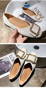 Elegant white flat shoes featuring a decorative square rhinestone buckle and soft leather.