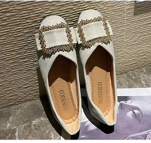 Macro detail view of elegant off-white women's flats with a large golden buckle