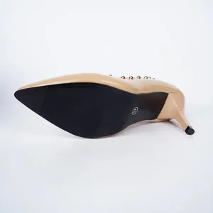 Detaillierte Ansicht der Sohle und des Stiletto-Absatzes eines beigen Nietenschuhs.