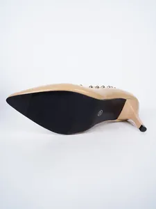 Detailansicht der rutschfesten Sohle und des Stöckelabsatzes am beigen Nietenschuh.