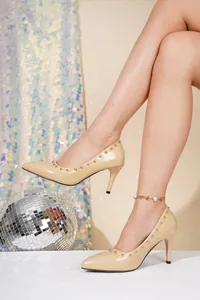 Detailansicht beige Pumps mit spitzer Zehenpartie und eleganten goldenen Nieten.