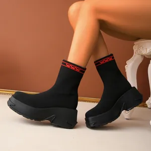 Side view of black fly-knit sock boots with chunky platform soles and red accents on top