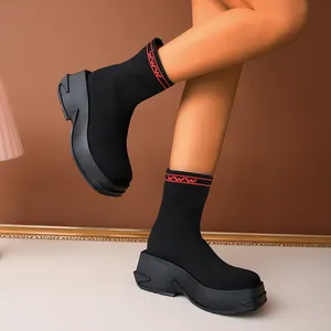 Close-up of black knit sock boots with thick platform soles and red cuff accents