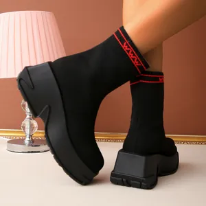 Detailed view of black knit platform sock boots with red wave pattern accents