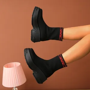 Side view of black fly-knit platform sock boots featuring red stripe details and chunky soles