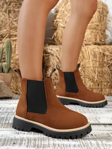 Detail view of brown suede Chelsea boots with chunky black lug soles and elastic sides