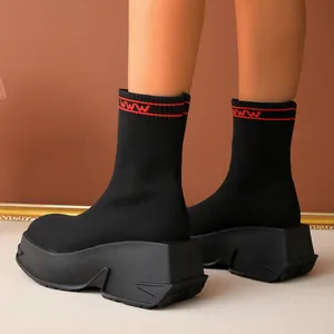 Close-up of black knitted sock boots with thick platform soles and red cuff stripe.