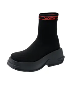 Detail shot of black knitted sock boot with red collar accents and platform sole.