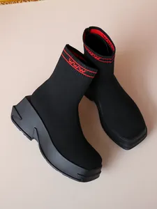 Detail view of breathable black knit sock boots with thick platform sole and red accents.