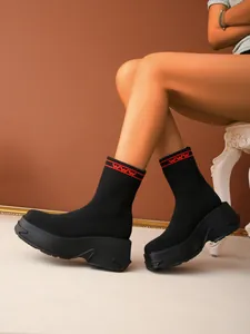 Close-up detail of black knitted platform sock boots with sporty red stripes and WWW text.